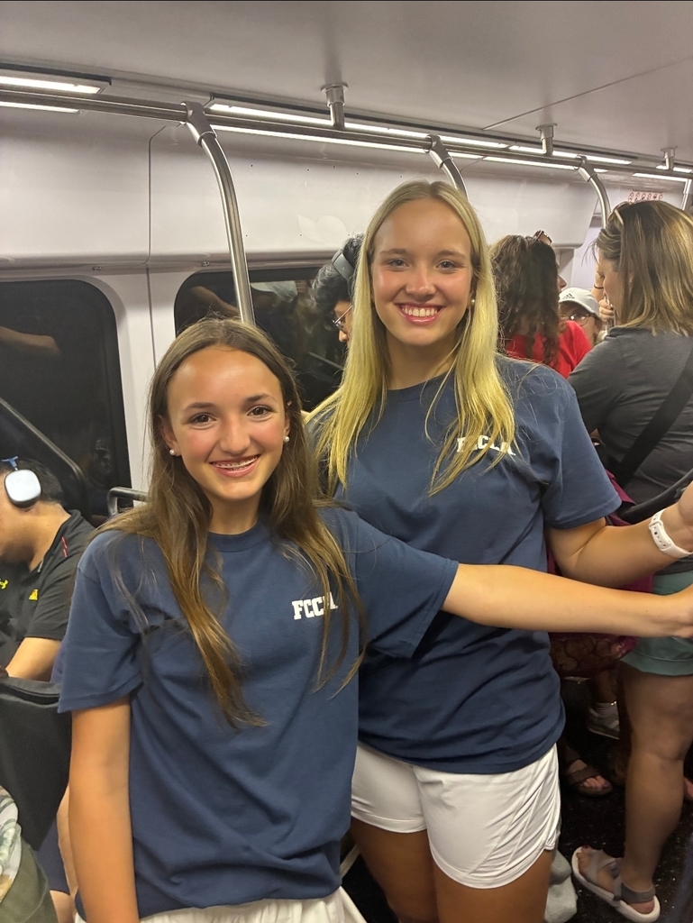 Two girls in FCCLA Tshirts stand on a subway