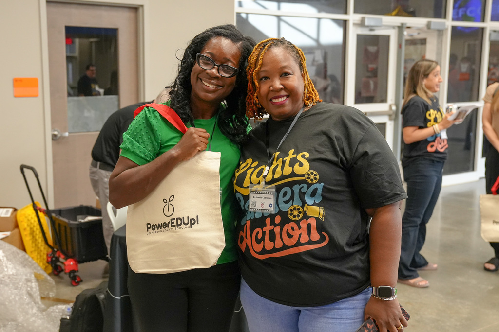 Two ladies stand together inside a building and smile for a photo.