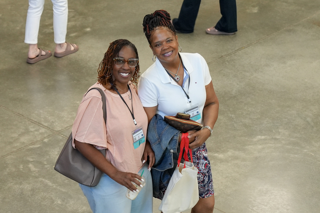 Two women pose for a photo inside a school building they stand together and smile.