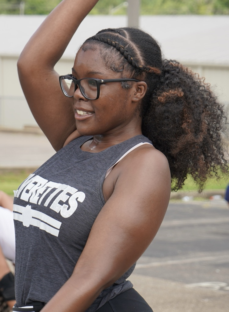 A girl smiles while practicing a dance routine in a parking lot