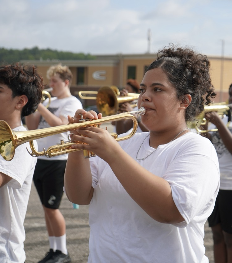 a girl stands in a parking lot and plays a trumpet