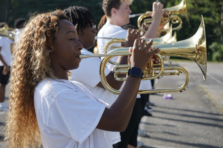 A girl plays an instrument while standing inside a parking lot