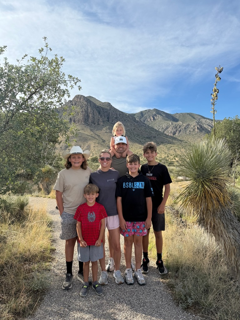 A family poses for a photo in front of mountains at Carlsbad Caverns National Park.