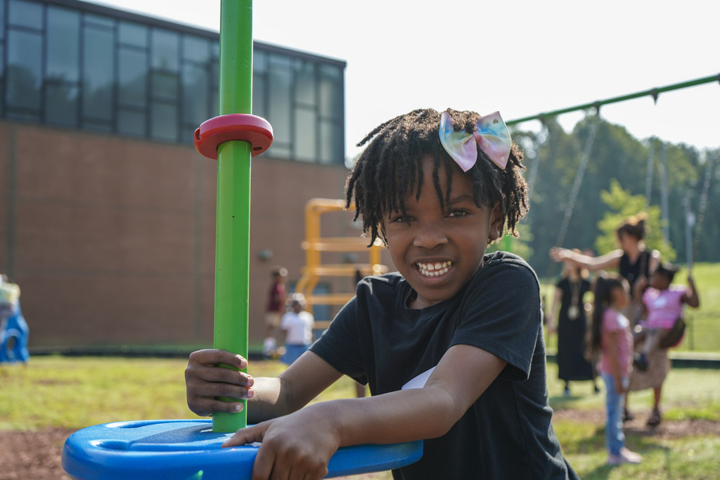 A child smiles while playing on a playground.