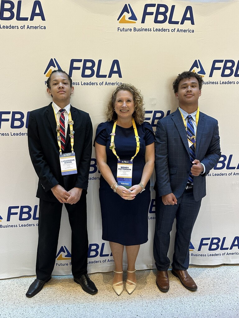 Three people stand in front of a banner that says FBLA, Future Business Leaders of America. 