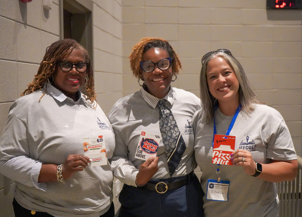 Three attendees at the 2026 JEFCOED Leadership Summit smile while holding up various restaurant gift cards. 