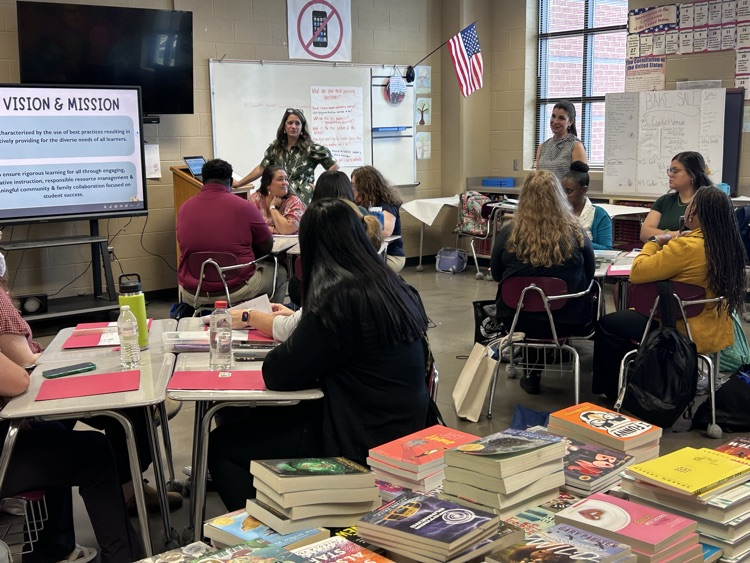 A woman speaks to adults while they sit in a classroom and listen