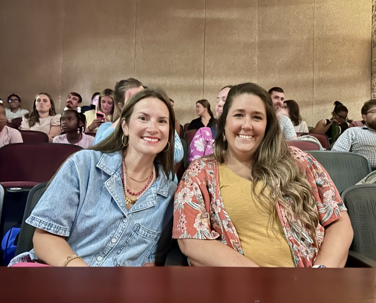 Two women sit in an auditorium and smile for a photo