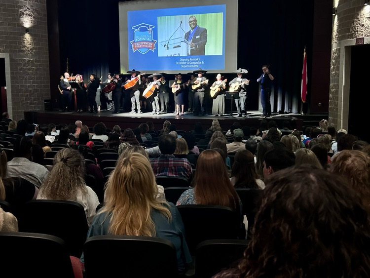 A mariachi band performs for adults as they sit in seats in an auditorium