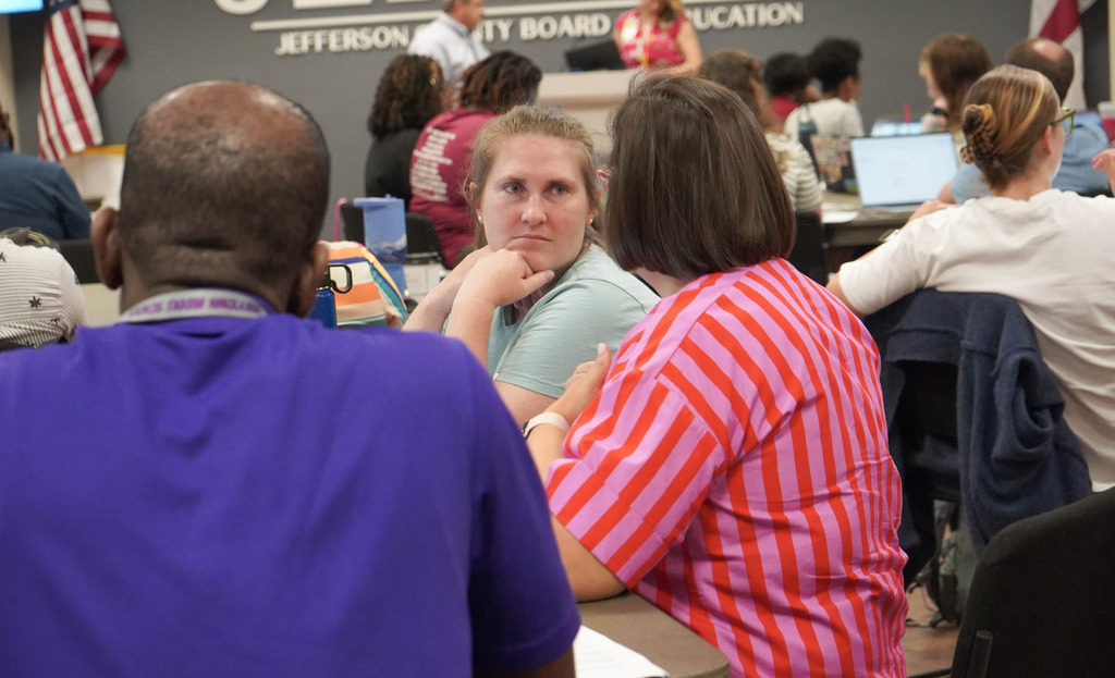 Educators sit at tables inside a room.