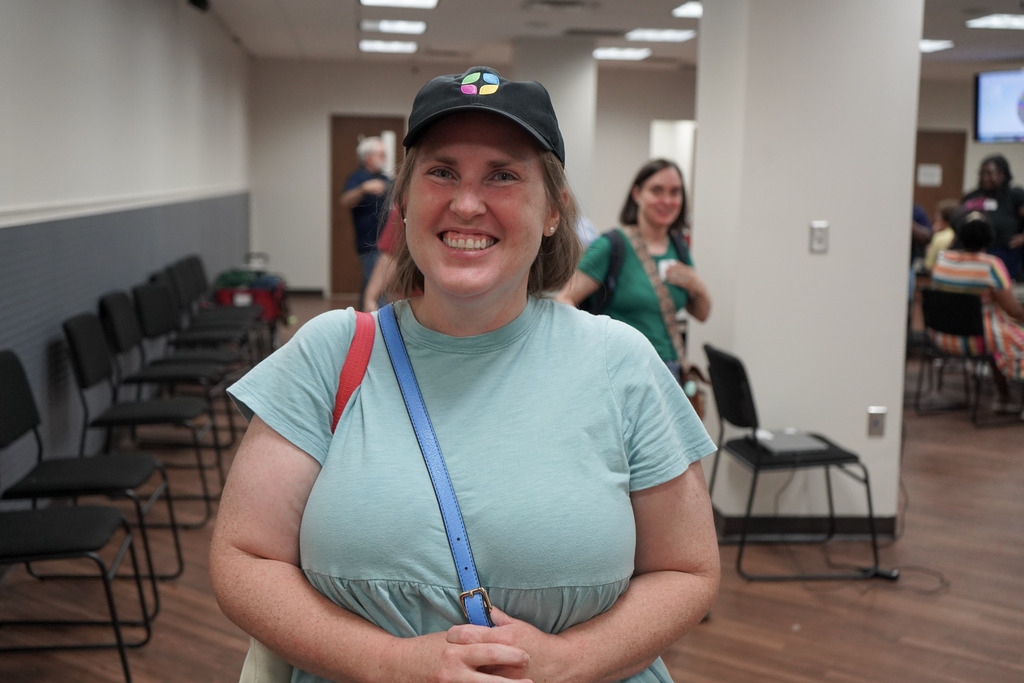 A woman stands in a room and smiles.