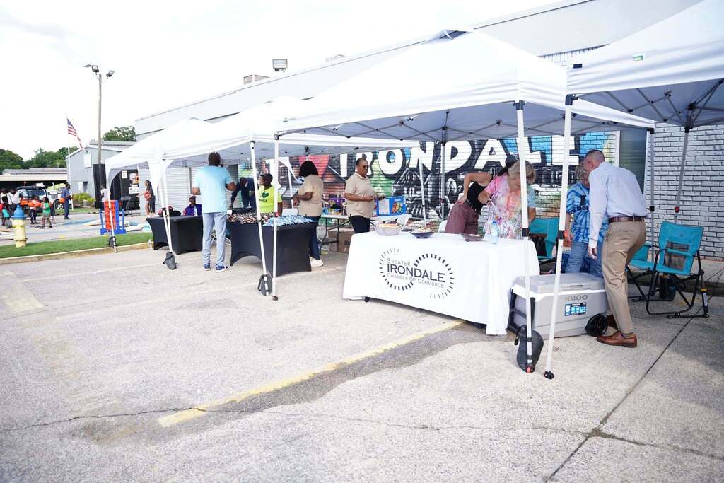 People stand under tents set up outdoors at a back to school rally.