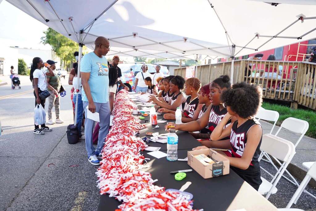 Shades Valley High School cheerleaders sit at a table under a tent and sign autographs.