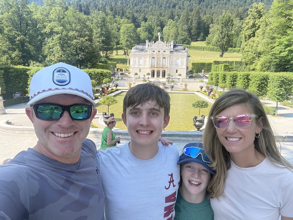 A family poses for a photo in front of Linderhof Palace in Bavaria, Germany.