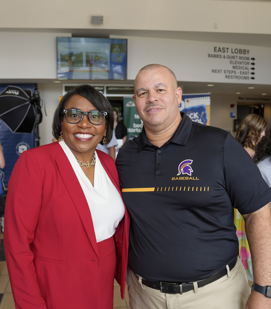 A woman and a man stand together and smile for a photo inside a room.