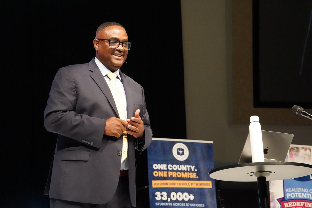 JEFCOED Superintendent Dr. Walter Gonsoulin stands on a stage and smiles while giving a speech.