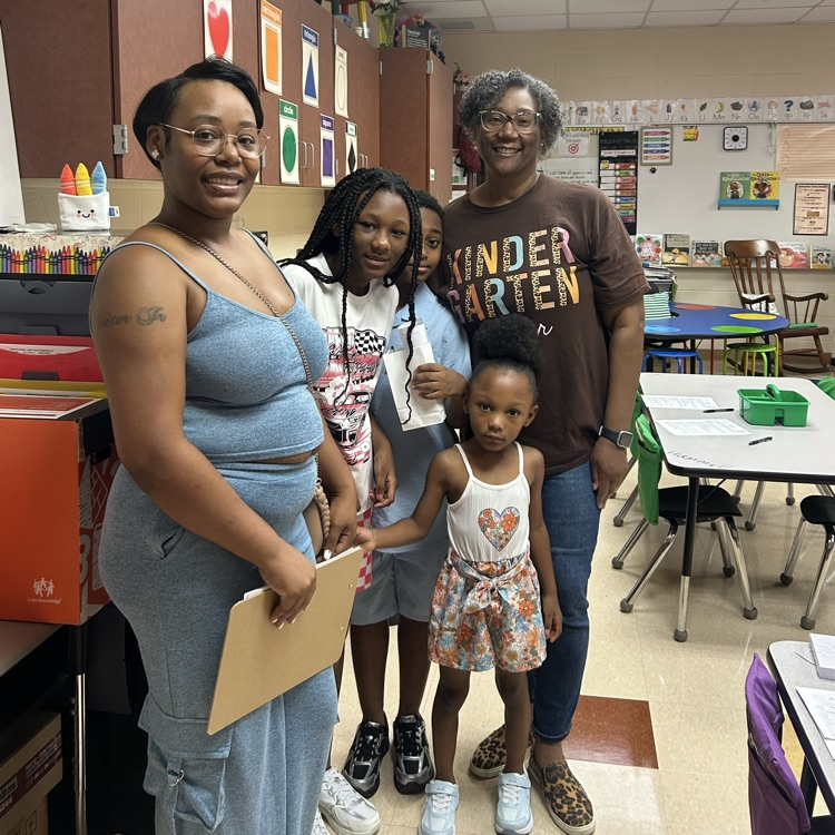 a teacher, parent, and children posing while smiling