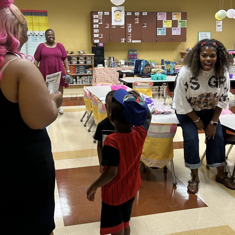 a teacher with a burst of excitement on her face greeting a student who is putting on a cap