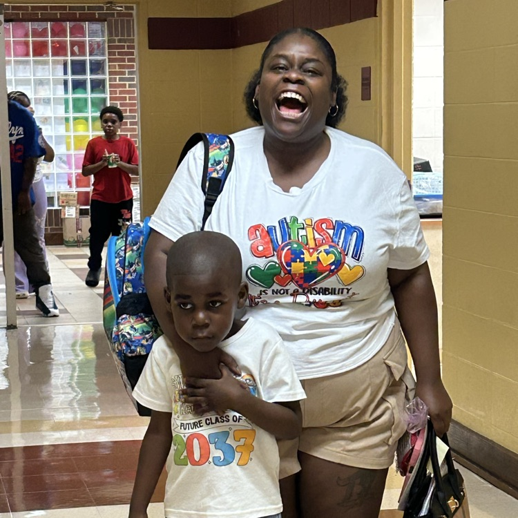 a parent laughing and hugging her son in the hallway of the school