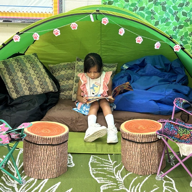 a student sitting in a tent reading a book in a classroom