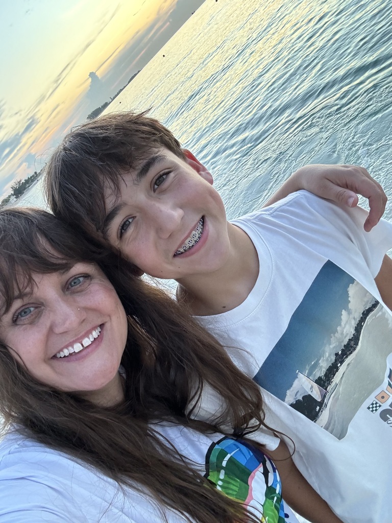 A woman and a child smiling in front of a body of water.