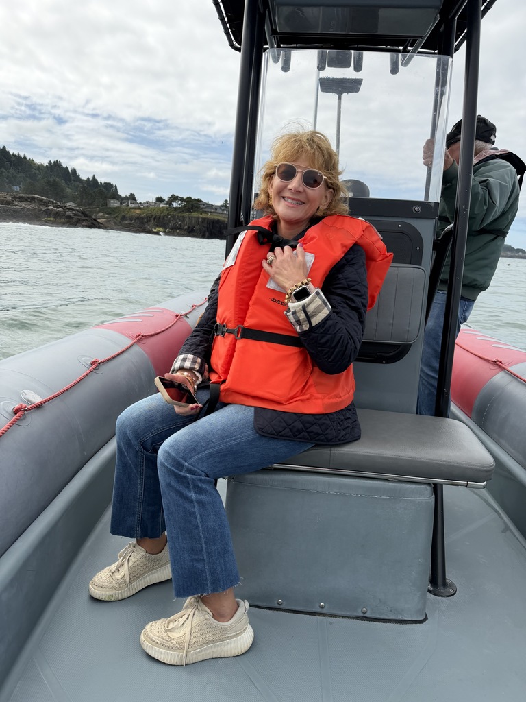 A woman sits on a boat in water and smiles for a photo.