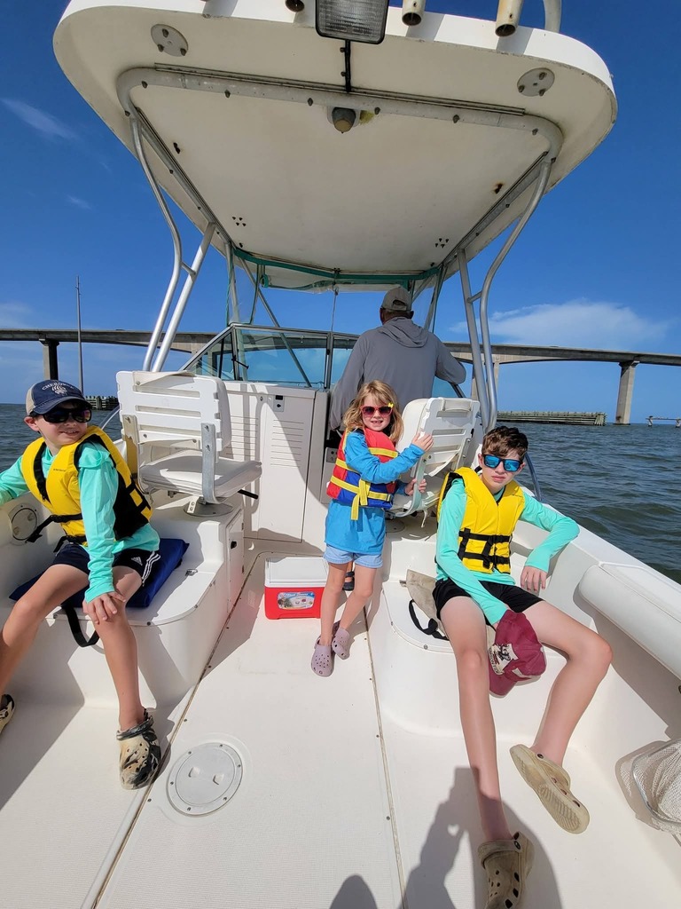 Children smile and pose for a photo while on a boat.