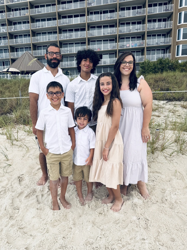 A family poses for a photo on a beach.
