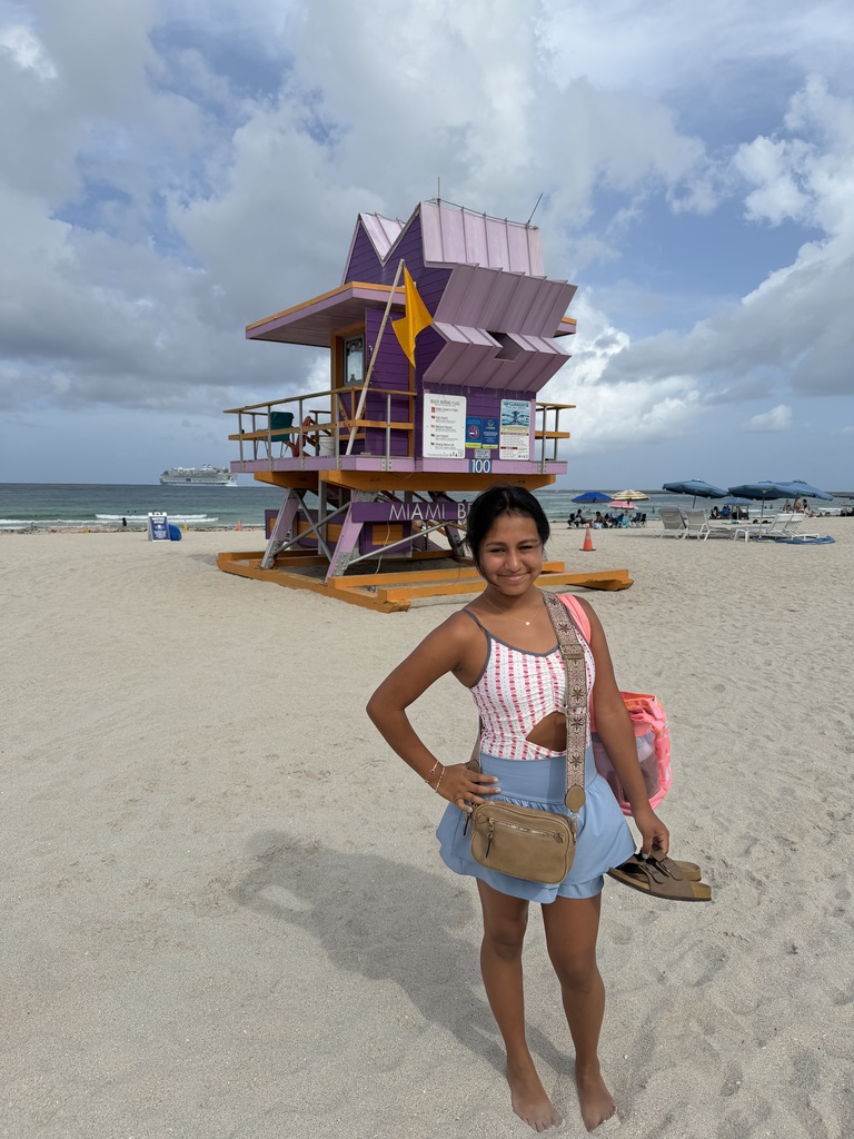A girl stands on a beach and smiles.