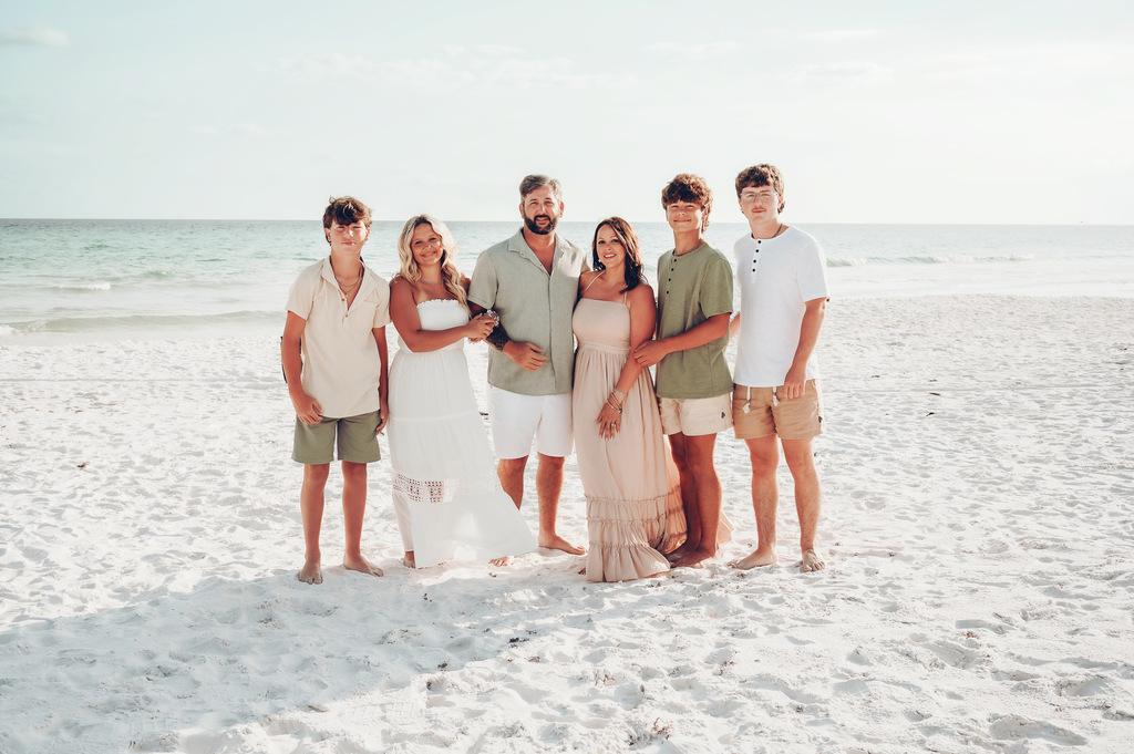 A family poses for a photo on a beach.