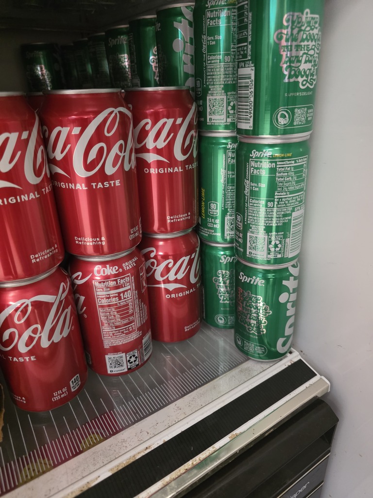 Coke and Sprite cans in the refrigerator. 