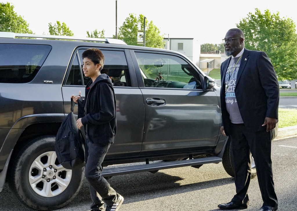 A man and a child walk toward a school after the child got out of the car during carpool.