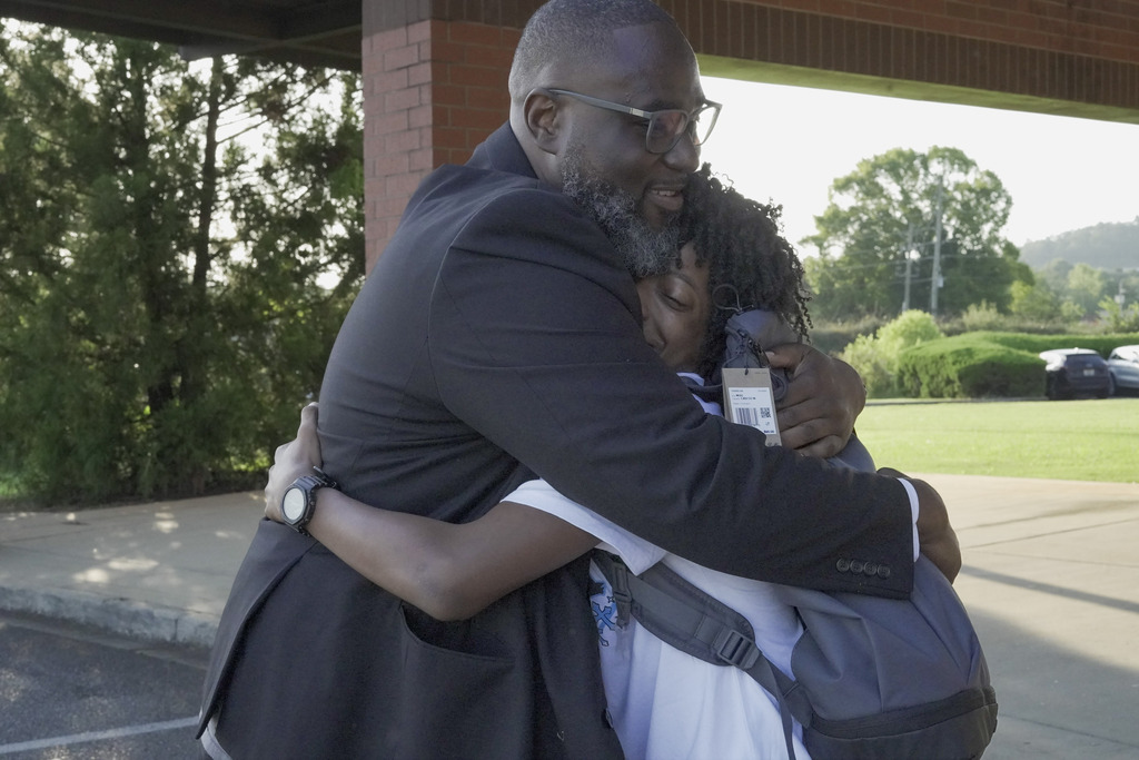 A man and a child hug outdoors.