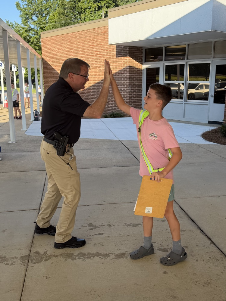 SRO officer and Safety patrol boy giving a high 5