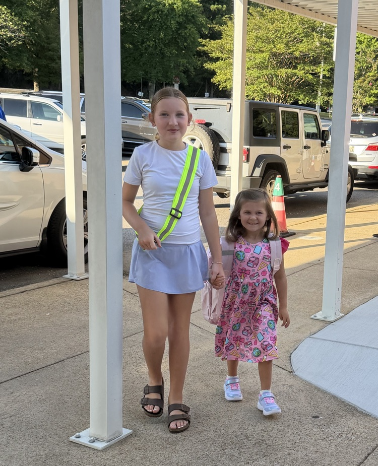 Safety Patrol girl holding hands with a young smiling girl