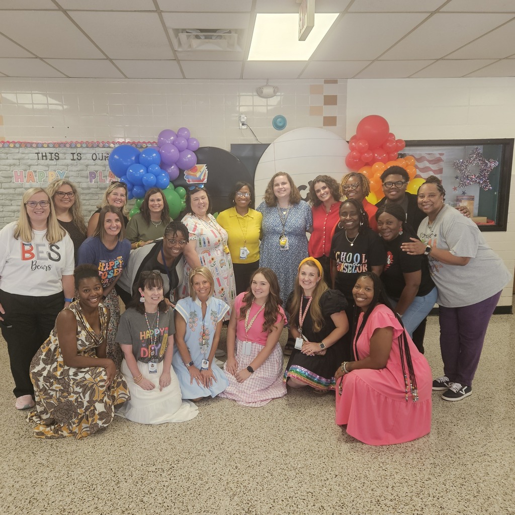 Teachers posing in front of balloons for a group picture.