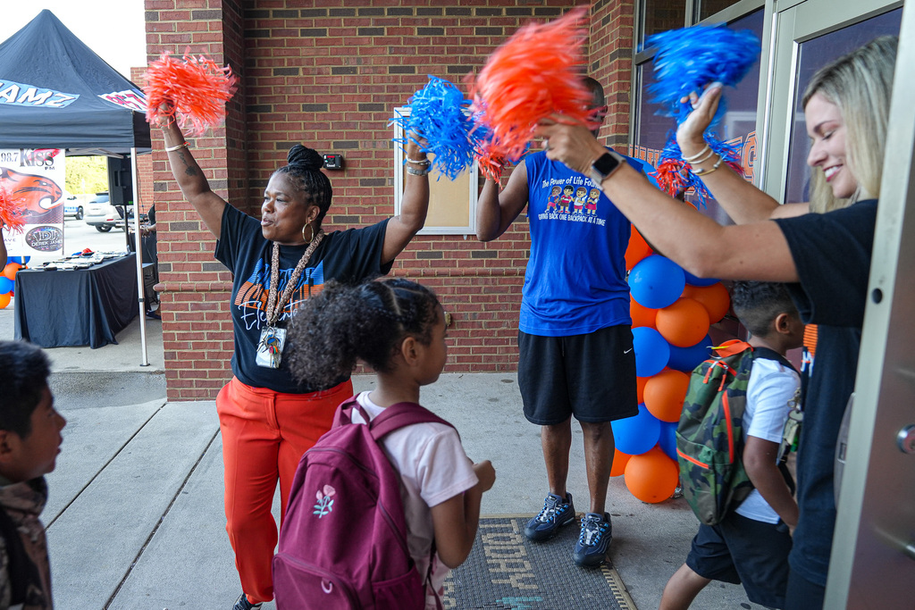 Staff at Fultondale Elementary wave orange and blue pom poms on the first day of school as students arrive.