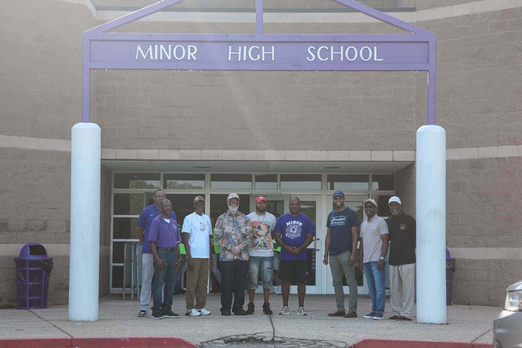 A group of men stand outside a school.