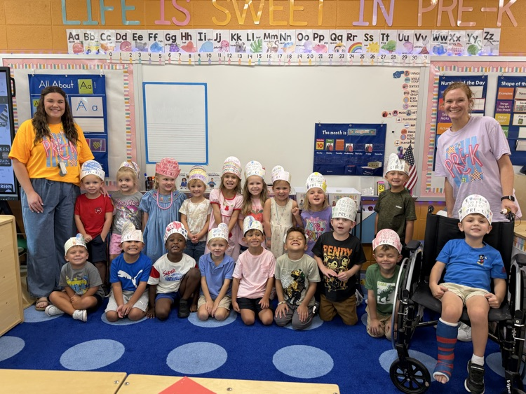 pre k class posing together with their teachers in their classroom 
