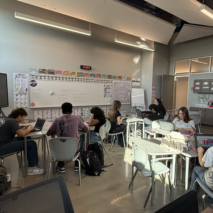 Several students in a Spanish classroom working on Chromebooks.
