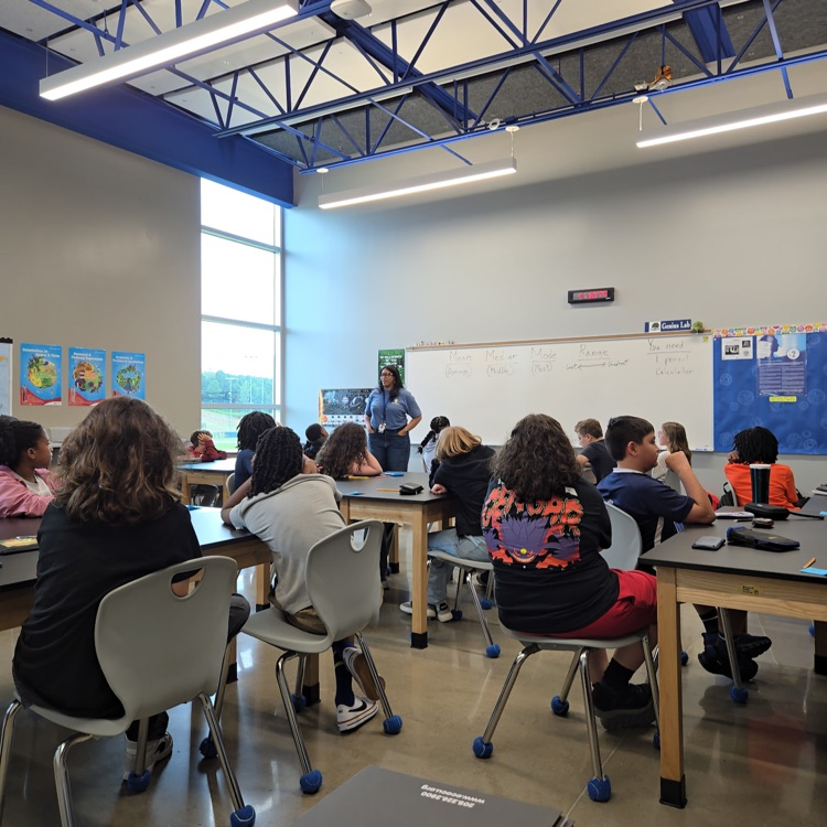 Dr. Clark at the front of the room talking to a group of sixth grade students.