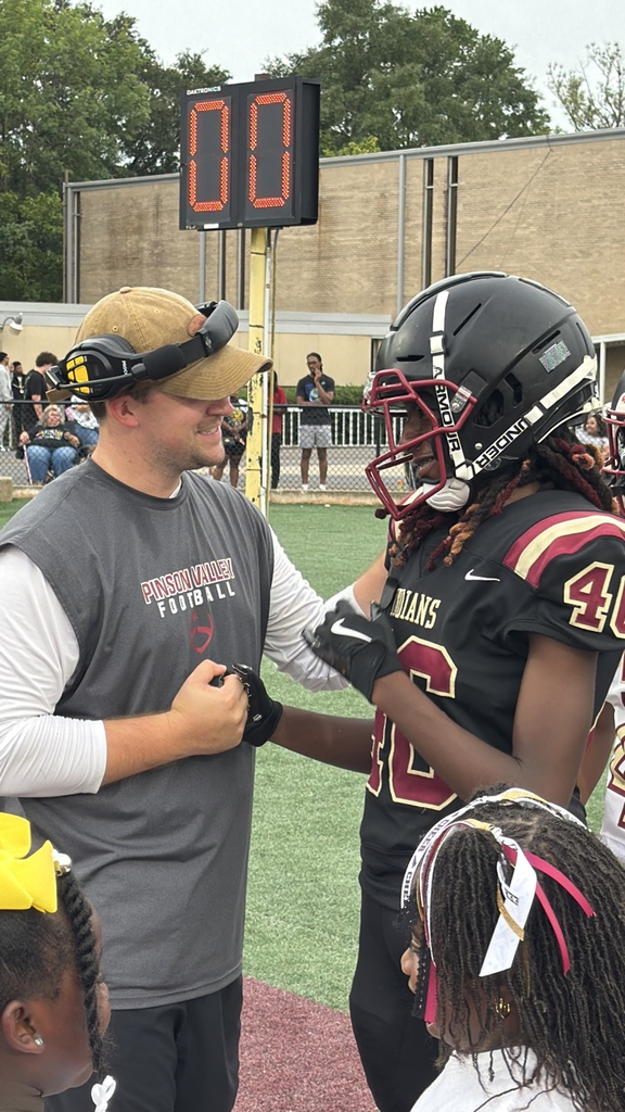 a coach shakes a players hand on the field before the game