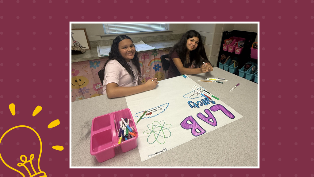 There are two girls happily working on a lab poster together