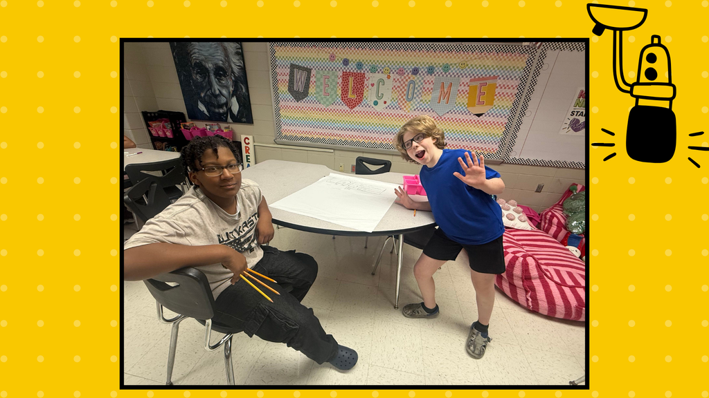 Two boys are suppose to work on a Science Lab poster, but stop to strike a silly pose.