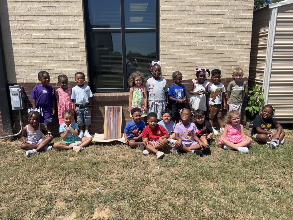 A group of students sitting with a tray of crayons that melted from the sun.