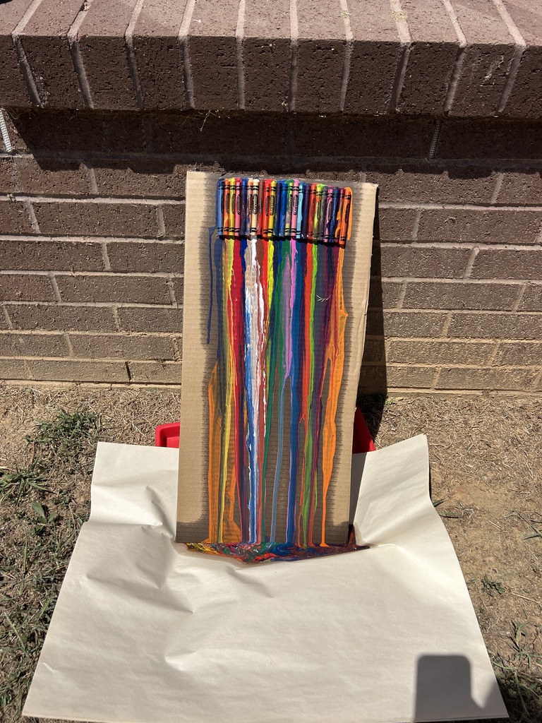 Crayons taped to a piece of cardboard that have melted after sitting in the sun.
