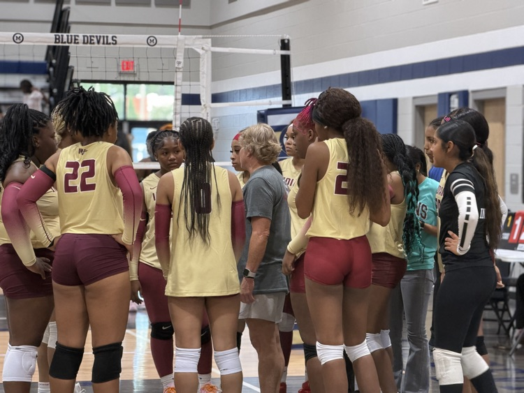 the varsity volleyball team meets with the coach on the court