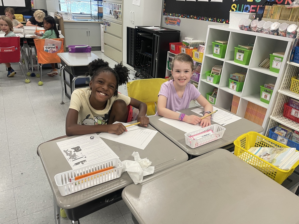 two students sitting at a desk writing