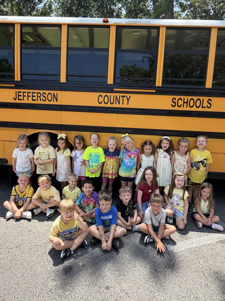 Kindergarten students ready for the first full week of school standing in front of a yellow school bus.