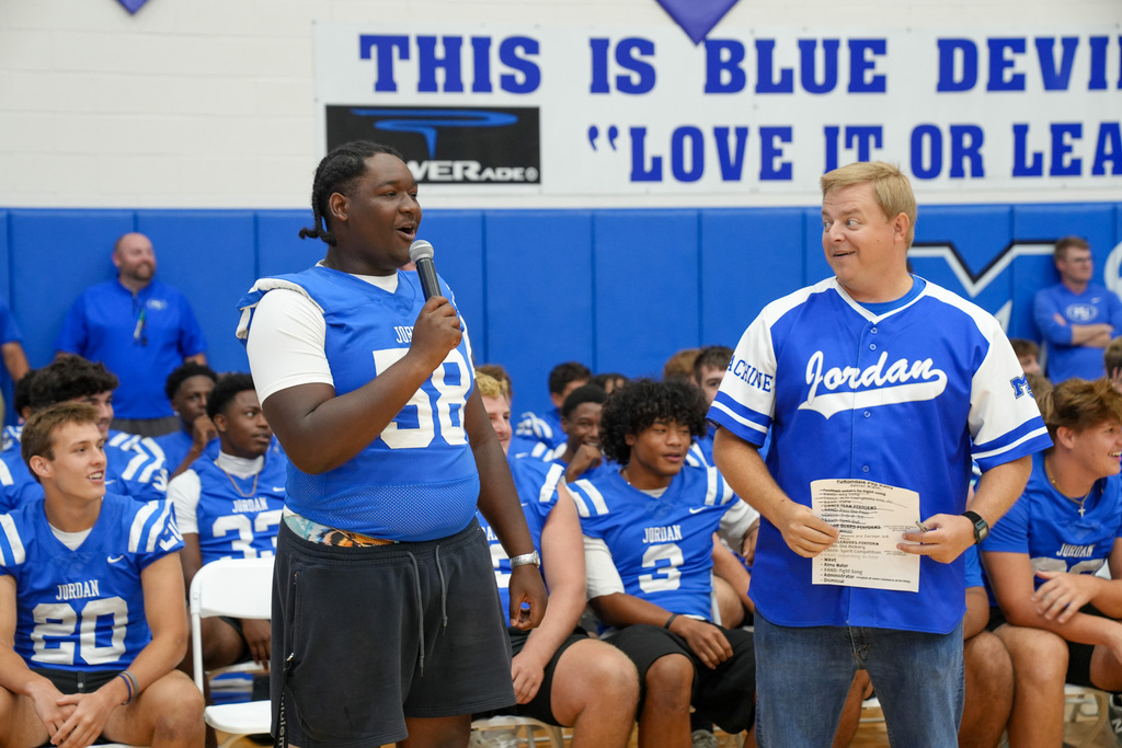 A Mortimer Jordan football player speaks into a microphone during a pep rally.